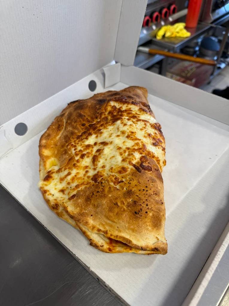 Polbeth golden-brown baked calzone inside an open white delivery box in Livingston.