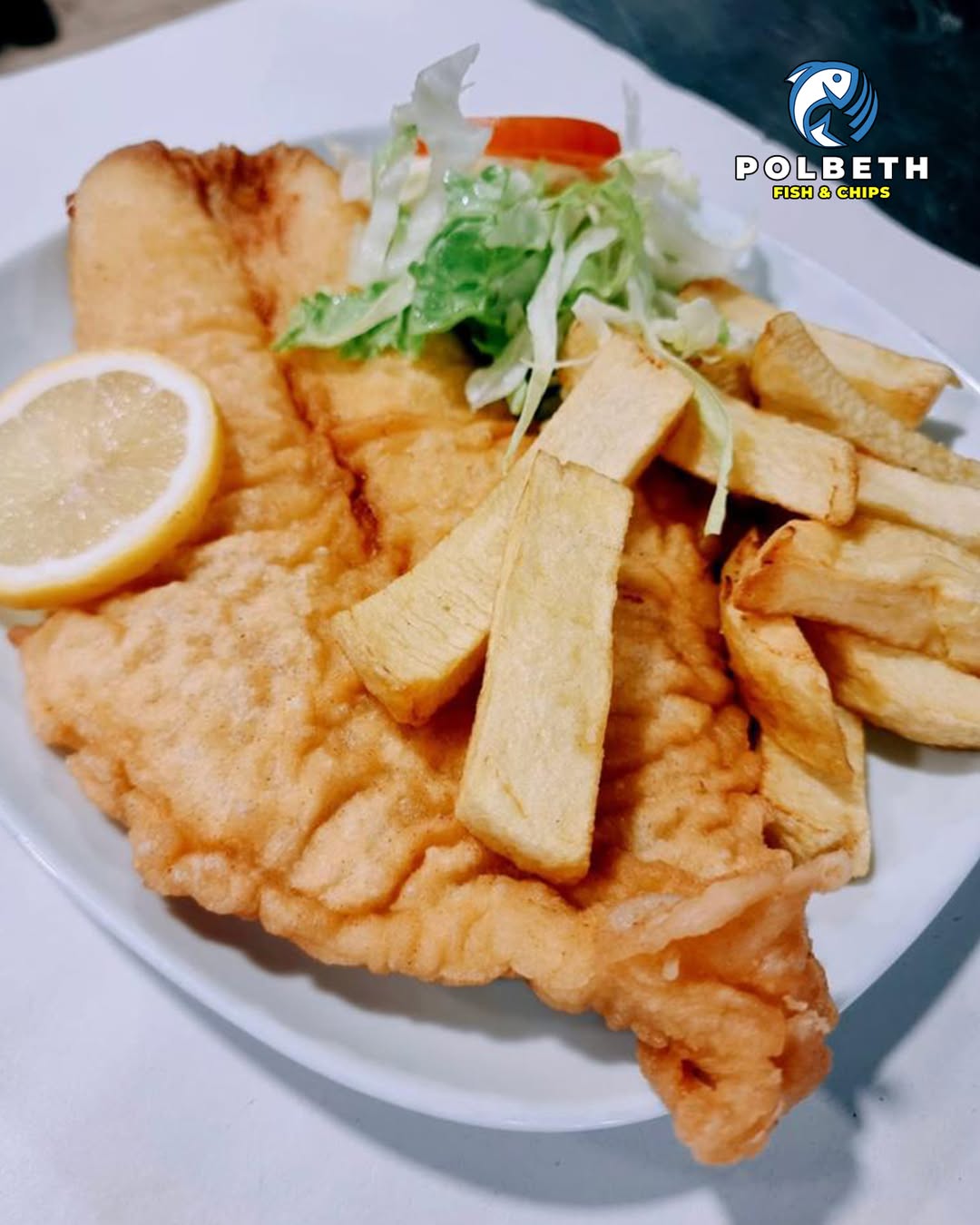 Golden battered fish served with thick-cut chips, a lemon slice, and salad at Polbeth Takeaway in Livingston.